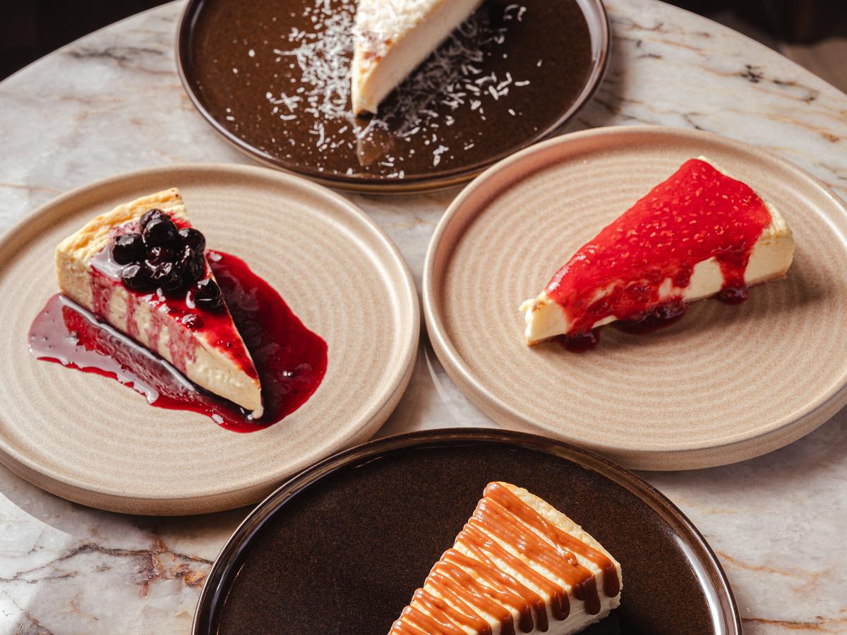 Cuatro rebanadas de gazta tarta AUPA con toppings distintos: coco, blueberry, frambuesa y caramelo salado