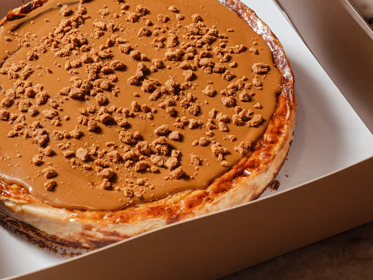 Tarta vasca de Lotus de AUPA en su caja, con cobertura de caramelo y migas de galleta